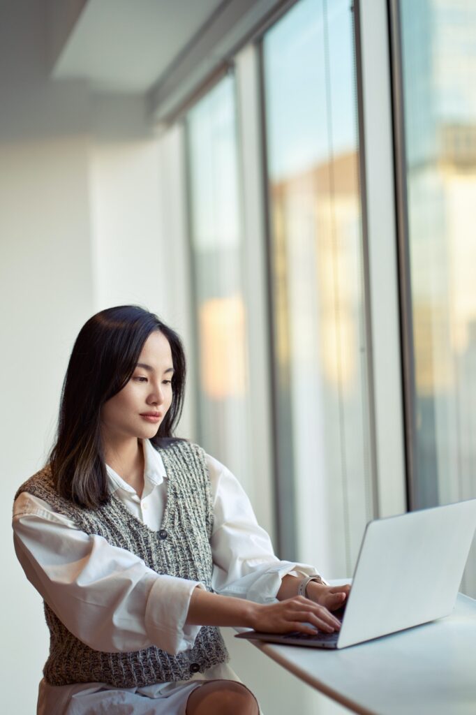Young pretty Asian business woman or student working on laptop in office.